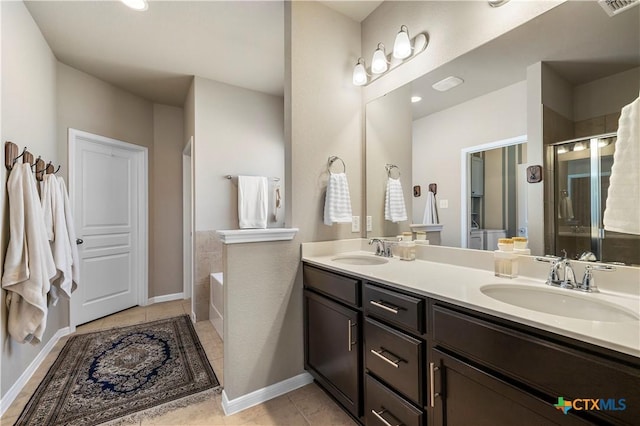 bathroom with double vanity, a stall shower, a sink, and tile patterned floors