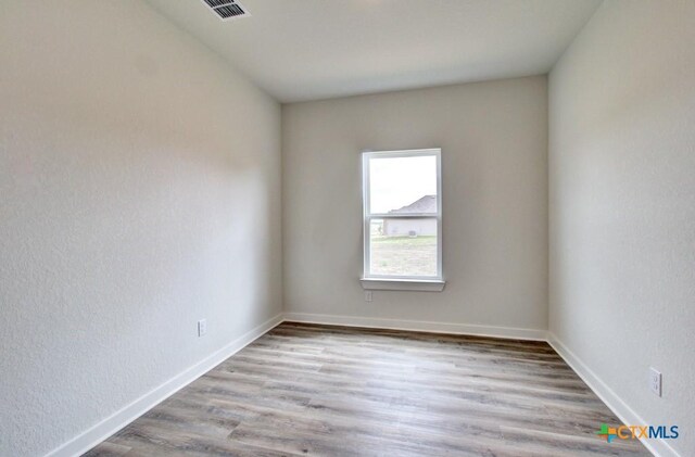 3644 Meteor Rd, New Braunfels, TX 78130 - empty room featuring wood finished floors, visible vents, a textured wall, and baseboards