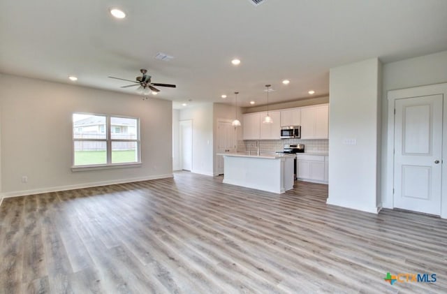 3644 Meteor Rd, New Braunfels, TX 78130 - kitchen featuring white cabinetry, appliances with stainless steel finishes, open floor plan, recessed lighting, and a kitchen island with sink