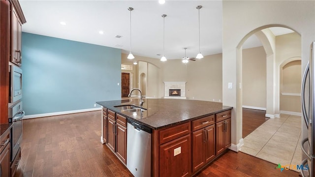 322 Wauford Way, New Braunfels, TX 78132 - kitchen with stainless steel appliances, a sink, a warm lit fireplace, dark wood-type flooring, and arched walkways