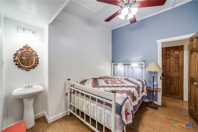 bedroom with wood walls, hardwood / wood-style floors, and ceiling fan