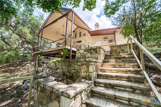 back of house featuring a deck, stairway, a ceiling fan, and a chimney