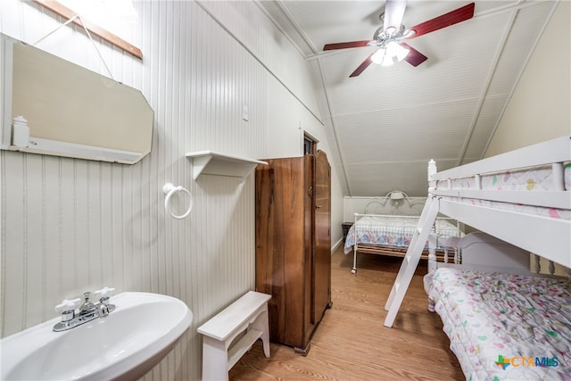 bathroom featuring wood walls, hardwood / wood-style flooring, sink, ceiling fan, and lofted ceiling