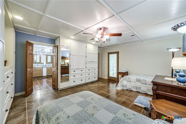 bedroom with dark tile patterned floors, connected bathroom, and a ceiling fan