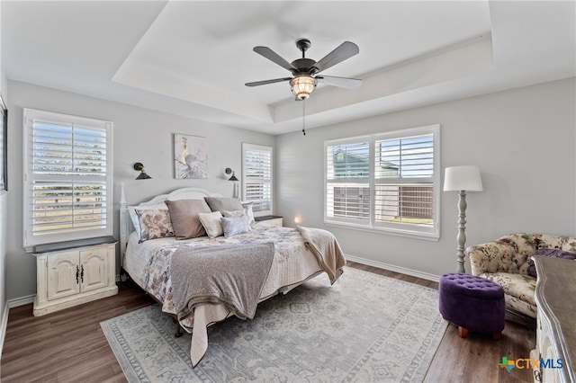 bedroom featuring dark hardwood / wood-style floors, multiple windows, and a raised ceiling