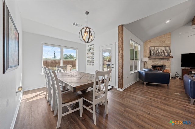 dining area featuring a chandelier, vaulted ceiling, dark hardwood / wood-style floors, and a fireplace