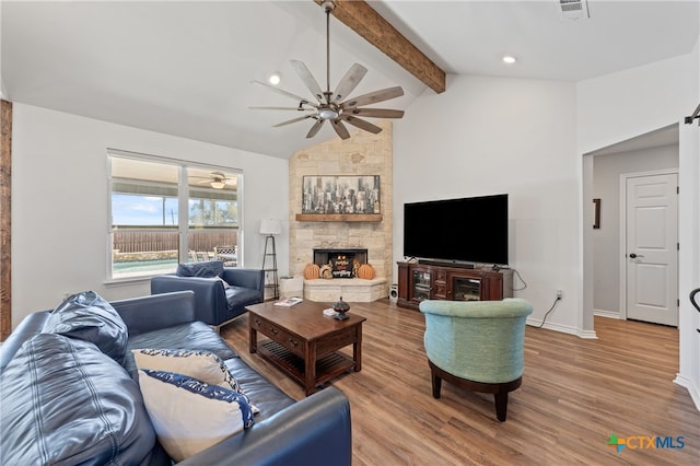 living room featuring lofted ceiling with beams, a stone fireplace, hardwood / wood-style floors, and ceiling fan