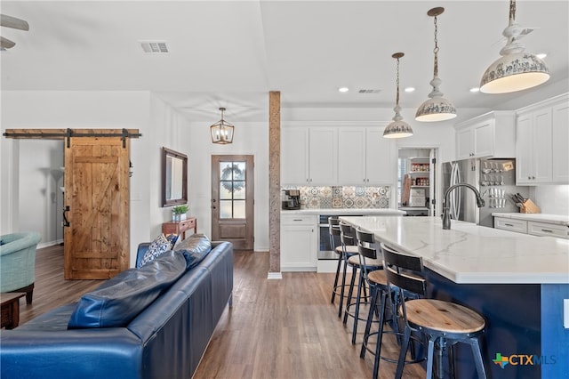 kitchen with white cabinetry, light hardwood / wood-style floors, a barn door, and decorative light fixtures