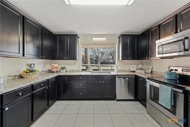 kitchen with light stone countertops, appliances with stainless steel finishes, light tile patterned floors, and sink