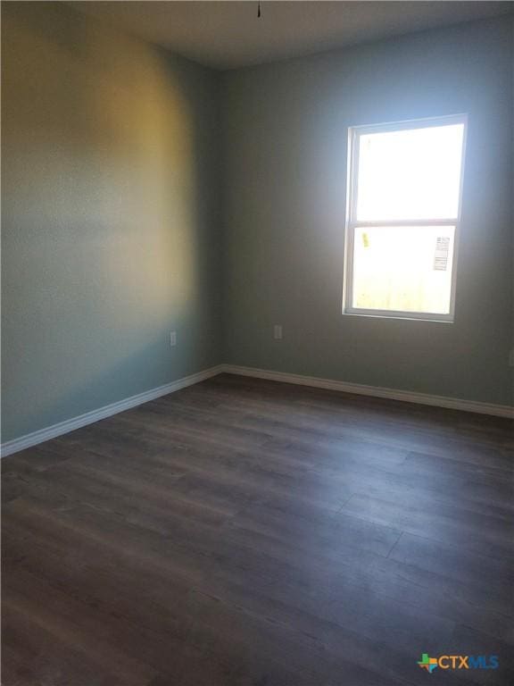 unfurnished room featuring dark wood-style floors and baseboards