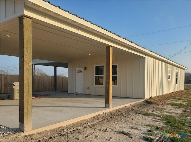 rear view of house with a patio area, fence, metal roof, and board and batten siding