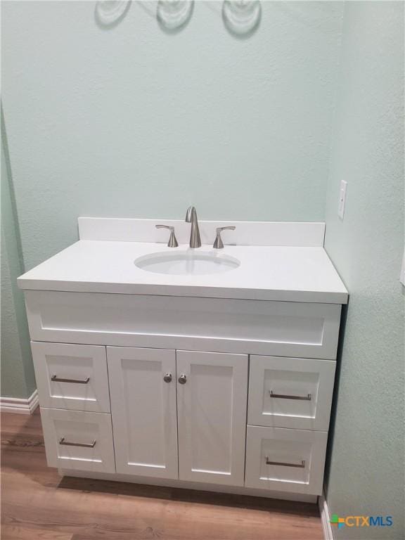 bathroom with vanity, baseboards, and wood finished floors