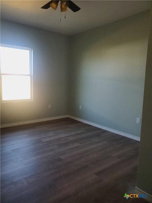 spare room featuring baseboards, ceiling fan, and dark wood-style flooring