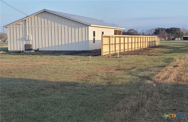 view of side of property featuring an outbuilding, cooling unit, a yard, and fence