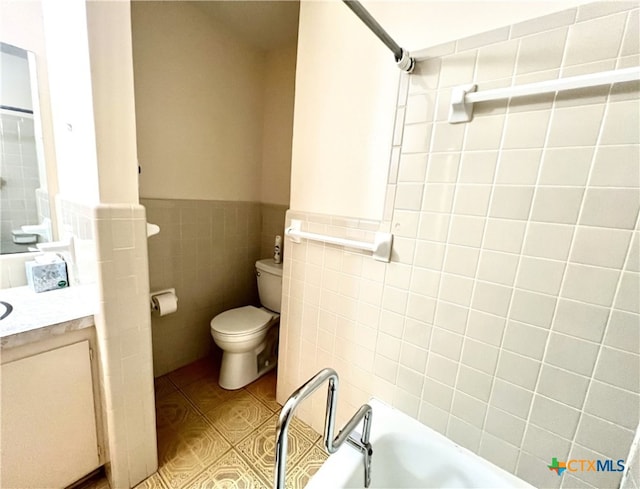 bathroom featuring vanity, a bathing tub, tile walls, and toilet