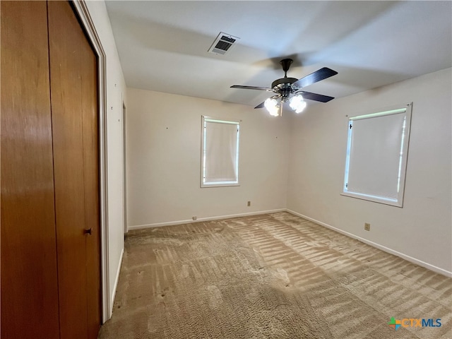 unfurnished bedroom with ceiling fan, light carpet, and a closet