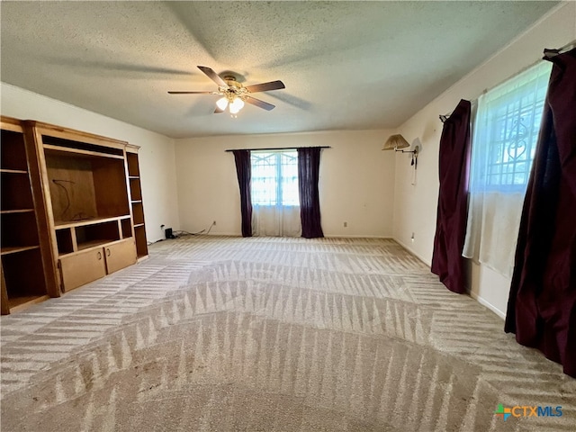 unfurnished bedroom with ceiling fan, a textured ceiling, and light carpet