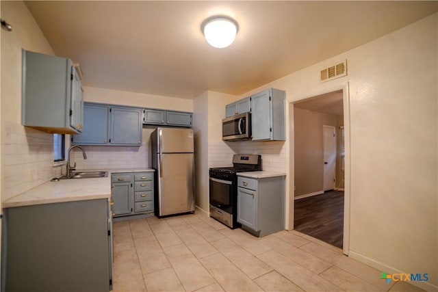 kitchen featuring appliances with stainless steel finishes, decorative backsplash, sink, gray cabinets, and light tile patterned flooring