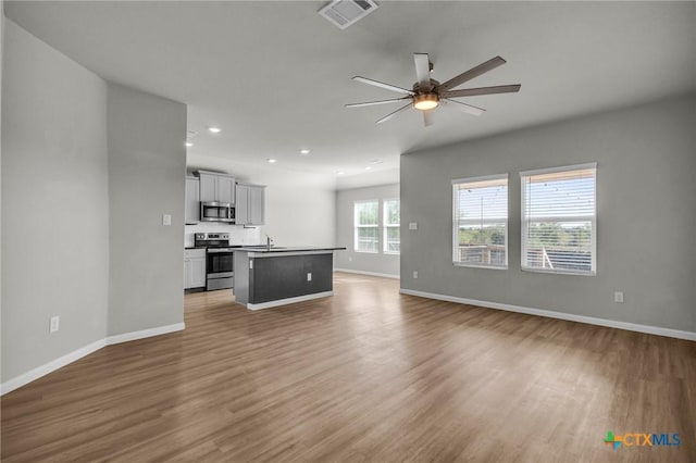 unfurnished living room with ceiling fan, wood-type flooring, and sink