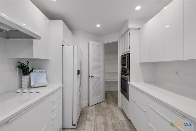 kitchen featuring recessed lighting, light wood-type flooring, white cabinetry, light countertops, and appliances with stainless steel finishes