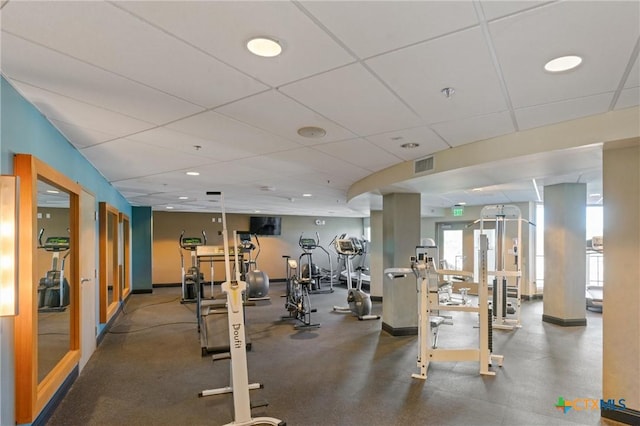 exercise room with visible vents, a paneled ceiling, and baseboards