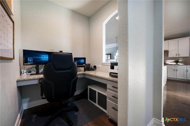 home office with dark wood-type flooring and built in desk