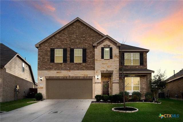 view of front of property with a garage, a yard, and central AC