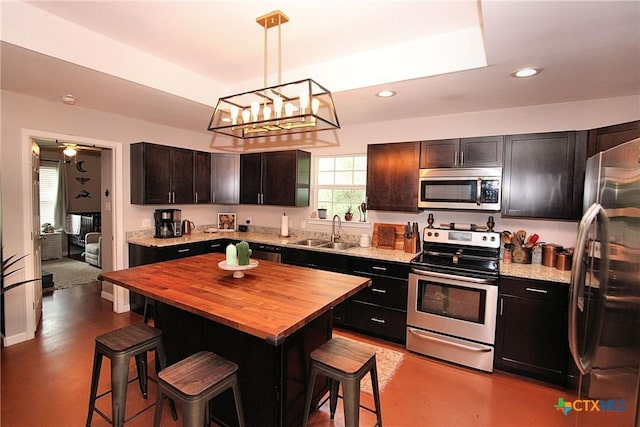 kitchen with stainless steel appliances, a kitchen breakfast bar, hanging light fixtures, a kitchen island, and sink