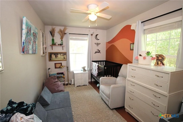 bedroom with ceiling fan and a nursery area