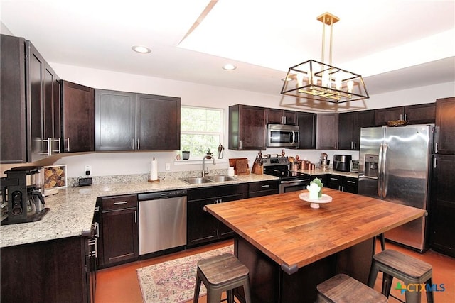 kitchen featuring dark brown cabinetry, appliances with stainless steel finishes, a center island, sink, and a breakfast bar area