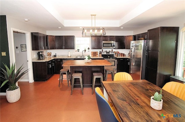 kitchen with pendant lighting, dark brown cabinetry, a center island, stainless steel appliances, and a breakfast bar