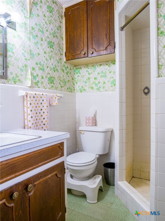 bathroom with toilet, vanity, tile walls, and a shower