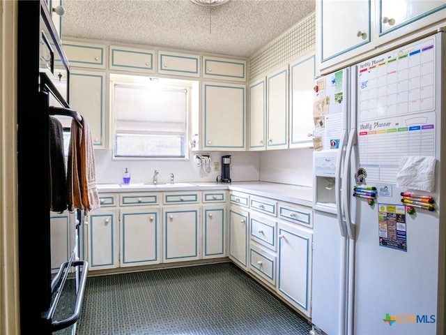 kitchen featuring dark colored carpet, white fridge with ice dispenser, a textured ceiling, and sink