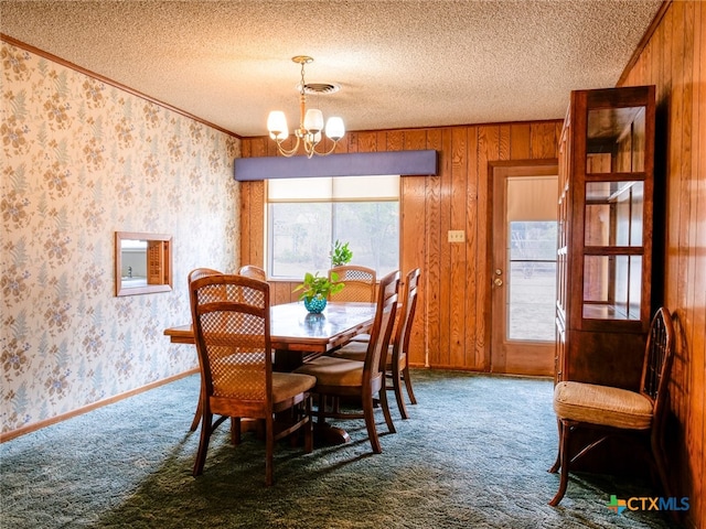 dining space with carpet flooring, wood walls, a textured ceiling, and crown molding