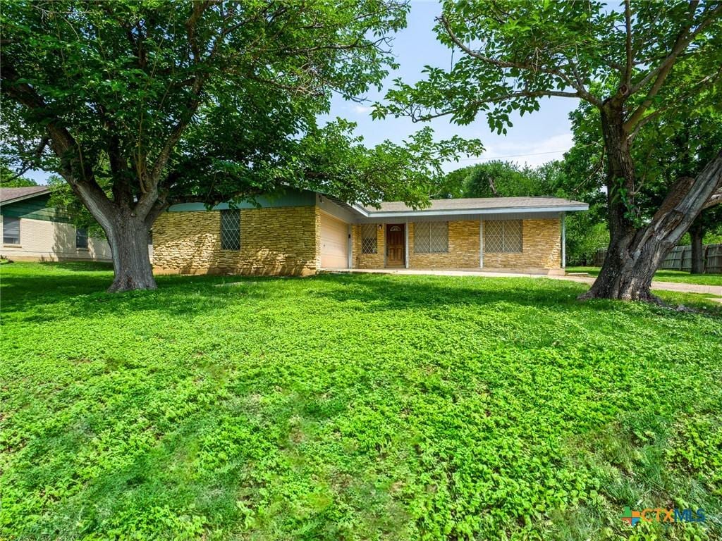 1107 Elm Ln, Marble Falls, TX 78654 - view of front facade featuring stone siding, a garage, and a front yard
