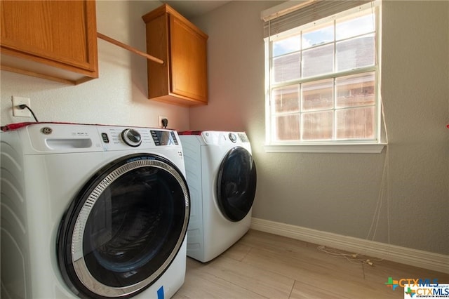 clothes washing area featuring cabinets, separate washer and dryer, plenty of natural light, and light hardwood / wood-style flooring