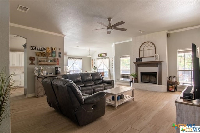 living room featuring a fireplace, a wealth of natural light, a textured ceiling, and light hardwood / wood-style floors