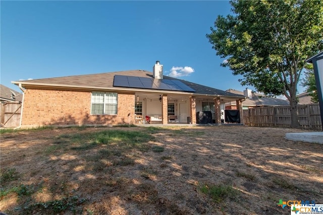 rear view of house with ceiling fan, solar panels, and a patio area