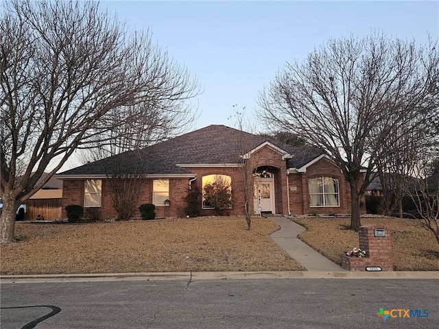 single story home featuring a shingled roof and brick siding