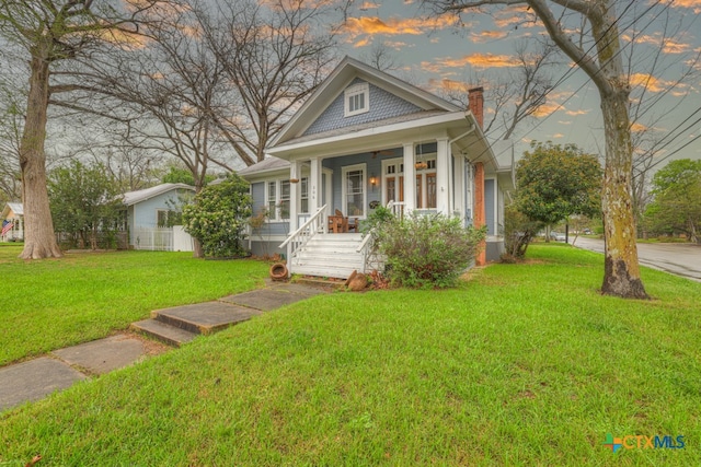 view of front of property with covered porch and a yard