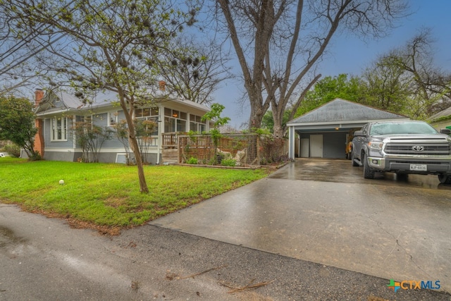 view of front of house featuring a garage, a front lawn, and an outdoor structure