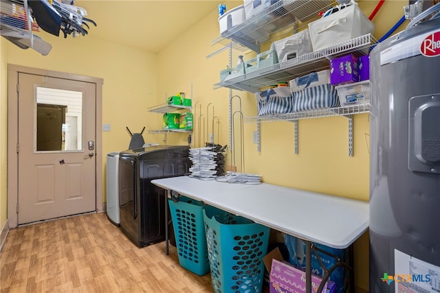 laundry room with electric water heater, washer and dryer, and light hardwood / wood-style flooring