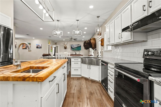 kitchen featuring light wood-type flooring, appliances with stainless steel finishes, wood counters, sink, and white cabinets