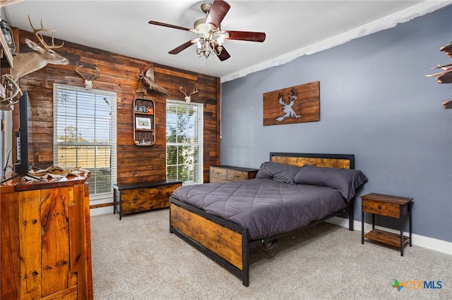 bedroom featuring wooden walls, light colored carpet, and ceiling fan