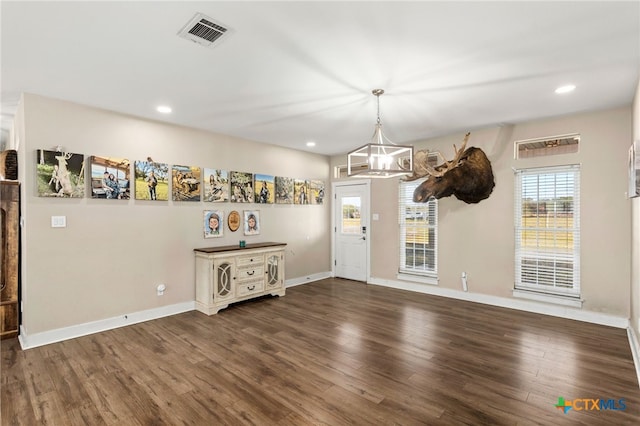 unfurnished dining area with dark hardwood / wood-style floors and an inviting chandelier