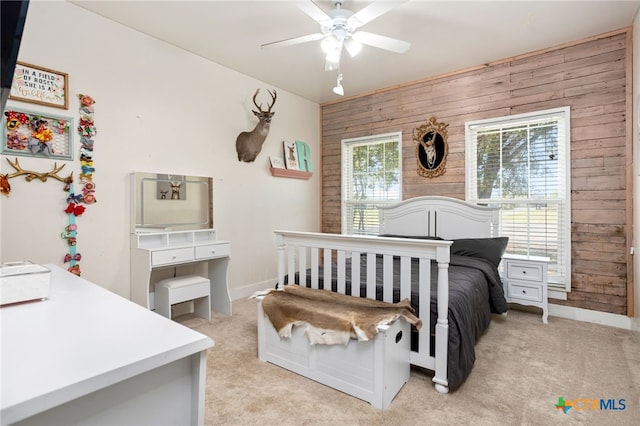 bedroom featuring wood walls, ceiling fan, and light carpet