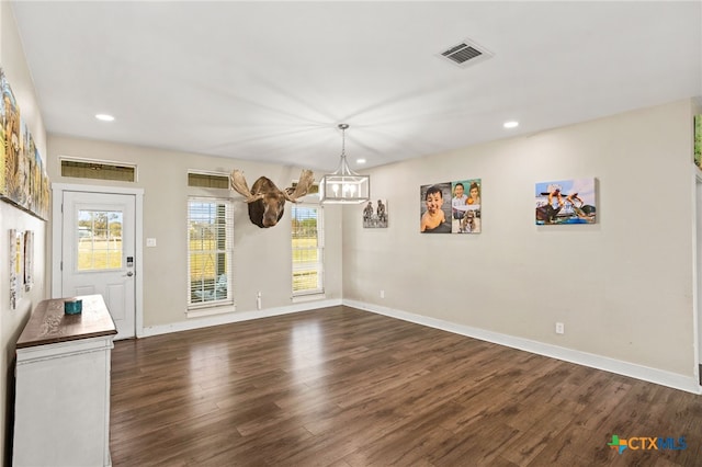 unfurnished dining area featuring dark hardwood / wood-style flooring and a notable chandelier