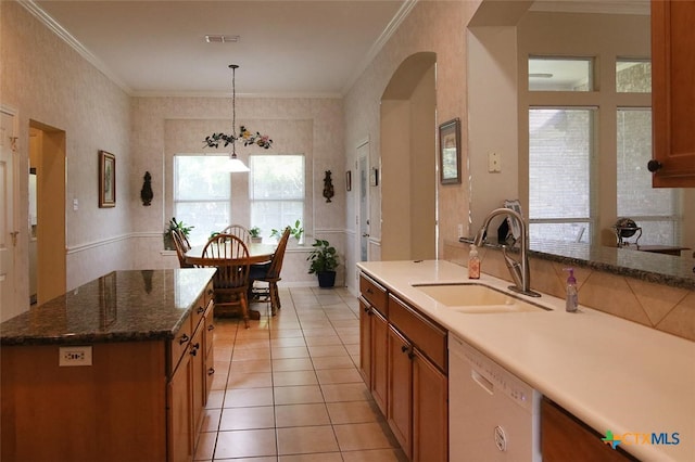 kitchen featuring sink, ornamental molding, white dishwasher, decorative light fixtures, and an island with sink