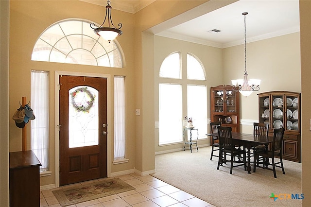 entrance foyer featuring a notable chandelier, light colored carpet, crown molding, and a towering ceiling