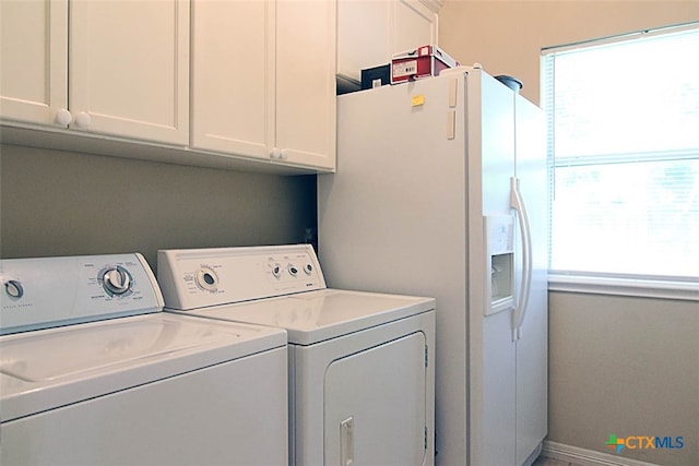 washroom with cabinets, washing machine and clothes dryer, and a healthy amount of sunlight